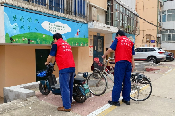 圖為志愿者規(guī)范擺放小區(qū)非機動車